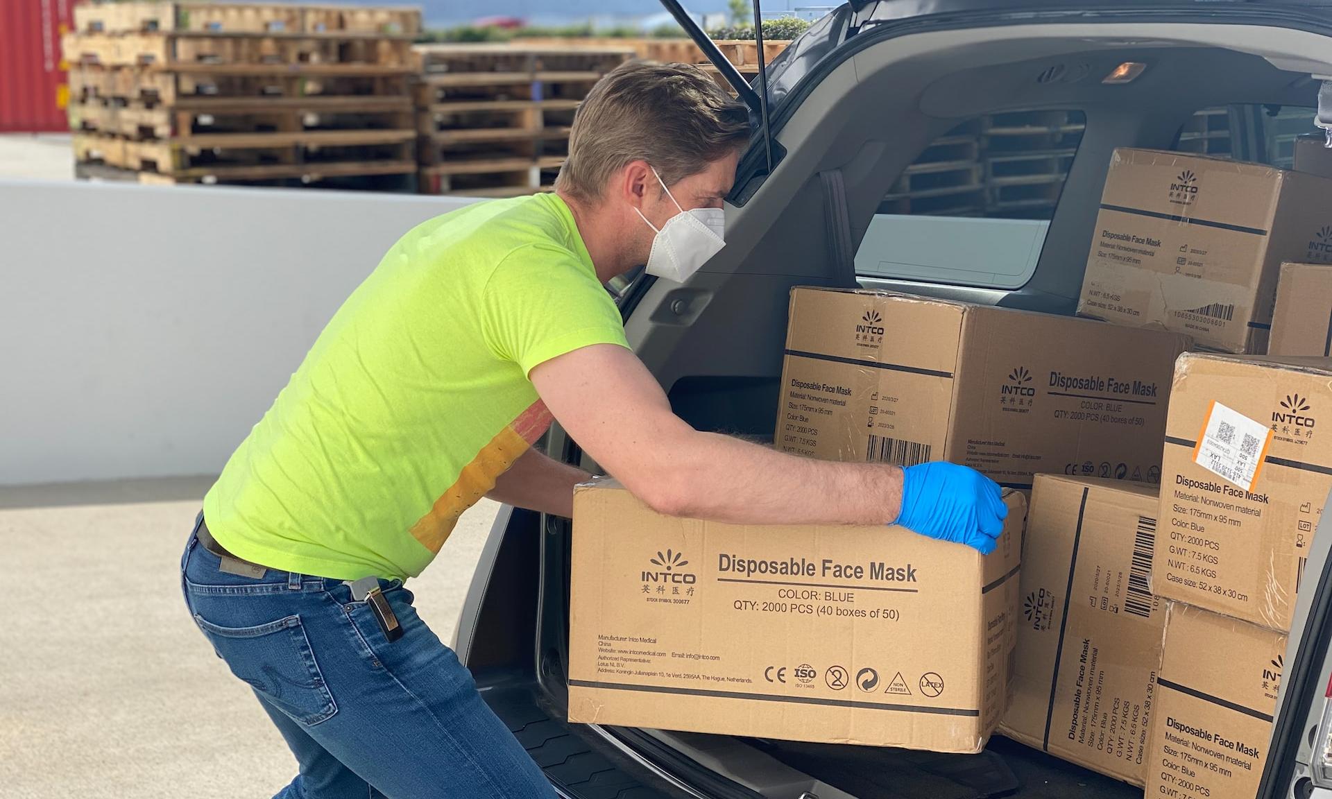 man in green t-shirt and blue denim jeans holding brown cardboard box